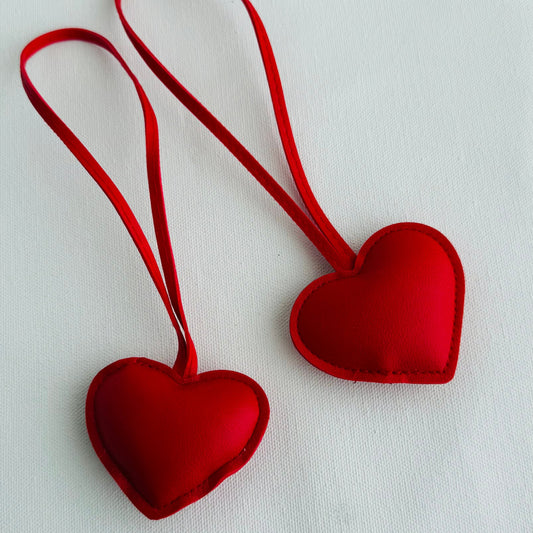 Two red heart-shaped keychains on a white background