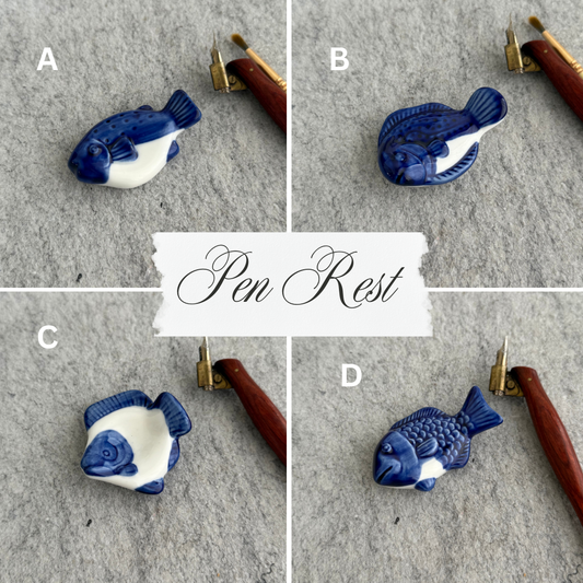 Blue and white fish-shaped pen rest on a gray surface with a white label in the center.