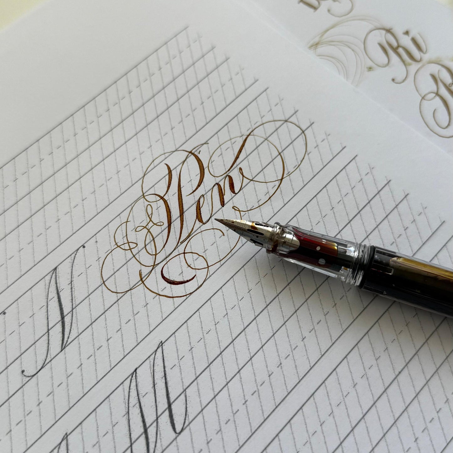 Calligraphy practice sheet with a pen on a white background